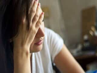 Woman with hand over face looking distressed 